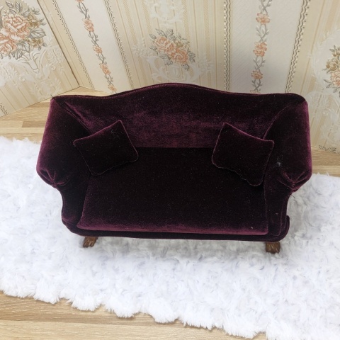 miniaturowa śliwkowa sofa z dwoma poduszeczkami